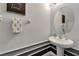 Stylish powder room featuring a pedestal sink, round mirror and black and white accent trim at 9720 Hound Chase Dr, Gibsonton, FL 33534