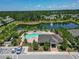 Aerial view of community pool and clubhouse surrounded by a serene pond and lush landscaping at 9720 Hound Chase Dr, Gibsonton, FL 33534