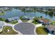 Aerial view of a waterfront home with lush landscaping, a circular driveway, and lake views at 1009 Andover Cir, Sun City Center, FL 33573