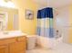 Bright bathroom featuring a bathtub with a shower, a vanity, and a colorful shower curtain at 101 8Th St, Belleair Beach, FL 33786