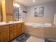 Well-lit bathroom with a soaking tub, wooden cabinets, and neutral tile flooring at 101 8Th St, Belleair Beach, FL 33786