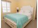 Inviting bedroom with a white headboard bed, complemented by yellow walls and shuttered windows at 101 8Th St, Belleair Beach, FL 33786