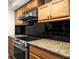 Close-up on oven, granite countertop, maple cabinets, and black backsplash at 10355 Paradise Blvd # 1003, Treasure Island, FL 33706