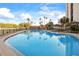 Relaxing pool area featuring palm trees and covered gazebos, perfect for outdoor enjoyment at 10355 Paradise Blvd # 1003, Treasure Island, FL 33706