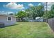 Expansive backyard with lush grass, a fenced perimeter, and mature trees offering shade at 10410 Ventura Ave, Tampa, FL 33619