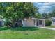 Inviting home with a well-manicured front yard, mature trees, and a charming screened-in porch at 10410 Ventura Ave, Tampa, FL 33619