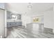 Open living space with modern gray wood-look floors and a view of the updated kitchen with stainless appliances at 1128 Eau Claire Cir, Tampa, FL 33619