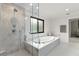 Bright bathroom featuring a soaking tub beneath a window and a glass-enclosed marble shower at 1139 43Rd N Ave, St Petersburg, FL 33703