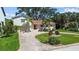 Charming home featuring a brick driveway, lush landscaping, and mature palm trees at 1238 Monterey Ne Blvd, St Petersburg, FL 33704