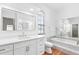 Bright bathroom featuring dual mirrors, white cabinets, gold hardware, and a marble trimmed tub at 12470 93Rd St, Largo, FL 33773