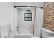 Bathroom featuring a shower over tub with white subway tiles, a mosaic accent wall, and a window at 12470 93Rd St, Largo, FL 33773