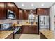 Modern kitchen featuring stainless steel appliances, granite countertops, and dark wood cabinetry at 12470 93Rd St, Largo, FL 33773