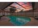 Twilight view of the enclosed pool area with string lights and plenty of patio space at 12470 93Rd St, Largo, FL 33773