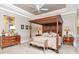 Elegant main bedroom features a four-poster bed, neutral colors, and tray ceiling at 14711 Potterton Cir, Hudson, FL 34667