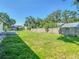 Lush, fenced backyard with green grass and mature trees, with a patio area at 1517 Gunsmith Dr, Lutz, FL 33559