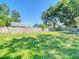 Expansive, fenced backyard with lush green grass and mature trees, perfect for outdoor activities at 1517 Gunsmith Dr, Lutz, FL 33559