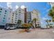 Exterior shot of the condo building with palm trees, parking, and a view of the beach at 1586 Gulf Blvd # 2502, Clearwater, FL 33767