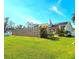 Large backyard with lush green lawn, a wood privacy fence, stone chimney and solar panels at 1608 20Th W Ave, Palmetto, FL 34221
