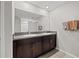 Bathroom featuring a double sink vanity with granite countertop and dark wood cabinets, complemented by a large mirror at 16632 Sunburst Lake St, Wimauma, FL 33598