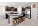 Modern kitchen with dark cabinets, granite countertops, stainless steel appliances, and a large island with bar stools at 16632 Sunburst Lake St, Wimauma, FL 33598