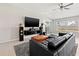 Cozy living room with a ceiling fan, large windows, and a comfortable black leather couch at 16632 Sunburst Lake St, Wimauma, FL 33598