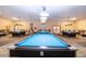 Well-lit billiards room featuring multiple pool tables with blue felt, pendant lighting, and comfortable seating at 1828 Foxhunt Dr # A, Sun City Center, FL 33573