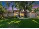 Charming one-story home featuring a light exterior, manicured lawn, mature trees, and a welcoming light blue front door at dusk at 1905 Horseshoe Dr, Plant City, FL 33566