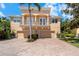 Charming two-story home featuring a balcony, three-car garage, brick driveway, and lush landscaping at 191 Banyan Bay Dr, St Petersburg, FL 33705