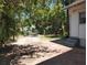 Spacious backyard area with a mix of concrete, sparse grass, mature trees and partial fencing at 1924 30Th S St, St Petersburg, FL 33712