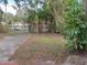 Large backyard featuring chain-link fence, mature trees, and a carport in the distance at 1924 30Th S St, St Petersburg, FL 33712
