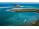 Aerial shot showcases a dock, sandy shoreline, and crystal-clear water on Honeymoon Island at 1926 Fairway W Cir, Dunedin, FL 34698