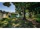 A serene backyard featuring lush green grass, mature trees and a charming home with an open backyard at 1926 Fairway W Cir, Dunedin, FL 34698