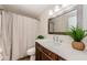 Bathroom boasts a modern vanity with sink, neutral curtain, and a decorative mirror at 1926 Fairway W Cir, Dunedin, FL 34698