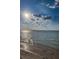 Sunlit beach with water and sand, under a partly cloudy sky at 1926 Fairway W Cir, Dunedin, FL 34698