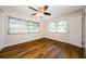 Bedroom featuring three windows, a ceiling fan, and wood flooring at 1926 Fairway W Cir, Dunedin, FL 34698