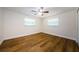 A bedroom with hardwood floors, two windows, and a ceiling fan, offering comfort and style at 1926 Fairway W Cir, Dunedin, FL 34698