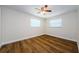 A bedroom with hardwood floors, two windows, and a ceiling fan, offering comfort and style at 1926 Fairway W Cir, Dunedin, FL 34698