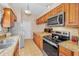 Kitchen with stainless-steel appliances, wood cabinets, tile floors, and granite countertops at 204 Lake Charles Ct, Oldsmar, FL 34677