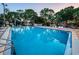Community pool with blue water, surrounded by mature trees, lounge chairs, and a playground at 204 Lake Charles Ct, Oldsmar, FL 34677