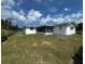 View of the home's backyard and screened in porch, with a well-manicured lawn and privacy fence at 2195 Academy Dr, Clearwater, FL 33764