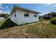 View of the side of the home and the backyard, showcasing the well-maintained lawn and privacy fence at 2195 Academy Dr, Clearwater, FL 33764