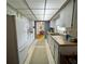 Galley kitchen featuring tile flooring, white cabinets, and view into dining area at 2195 Academy Dr, Clearwater, FL 33764