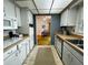 Galley kitchen featuring white cabinets, tiled flooring, and dining area beyond at 2195 Academy Dr, Clearwater, FL 33764