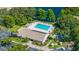 Aerial view of community pool with lounge chairs, landscaping, tennis court, and nearby lake at 2510 Laurelwood Dr # 5B, Clearwater, FL 33763