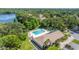 Aerial view of a sparkling community pool with tennis court, parking, and lush trees surrounding it at 2510 Laurelwood Dr # 5B, Clearwater, FL 33763