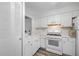 This galley kitchen features white appliances, cabinets, and wood-look flooring at 2928 Feather Dr, Clearwater, FL 33759