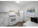 Bright kitchen features white cabinets, appliances, wood-look flooring, and window at 2928 Feather Dr, Clearwater, FL 33759