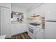 Bright kitchen features white cabinets, appliances, wood-look flooring, and view to living room at 2928 Feather Dr, Clearwater, FL 33759