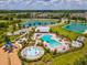 Aerial view of the community pool, splash pad, playground, clubhouse, lake, and landscaping at 33716 Elm Hill Br, Wesley Chapel, FL 33545