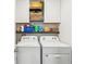 Functional laundry room with white washer and dryer units and storage cabinets at 33716 Elm Hill Br, Wesley Chapel, FL 33545